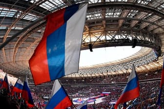 Menschen mit russischen Fahnen während des Auftritts von Wladimir Putin.