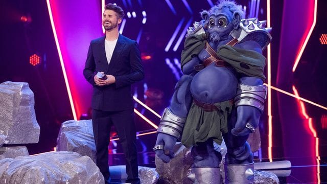 Vertretungs-Moderator Thore Schölermann steht neben der Figur "Der Ork" auf der Bühne.