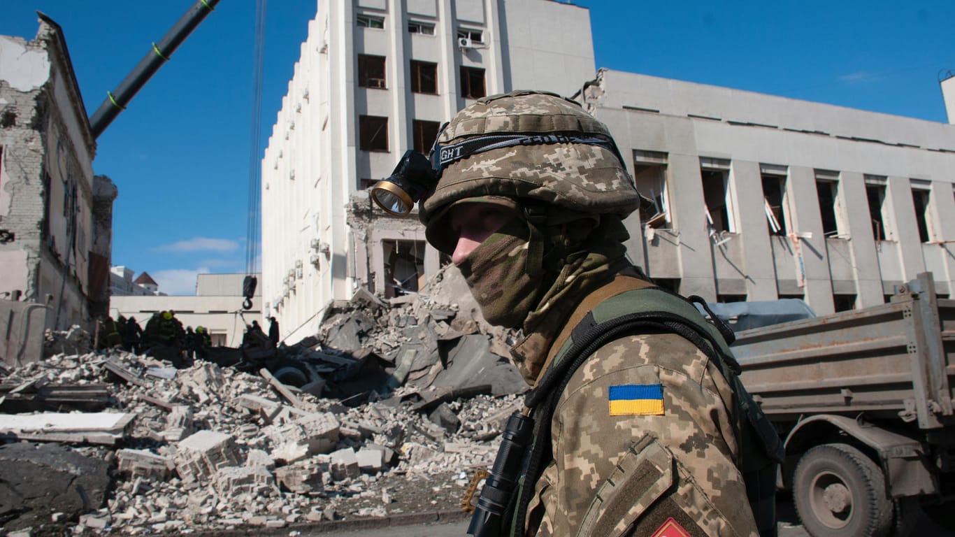 Ein ukrainischer Soldat bewacht das durch Beschuss beschädigte Gebäude der Nationalen Akademie für staatliche Verwaltung in Charkiw.