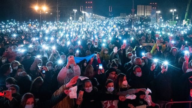 Zahlreiche Zuschauer leuchten mit ihren Handy-Taschenlampen bei "Sound of Peace" am Brandenburger Tor.