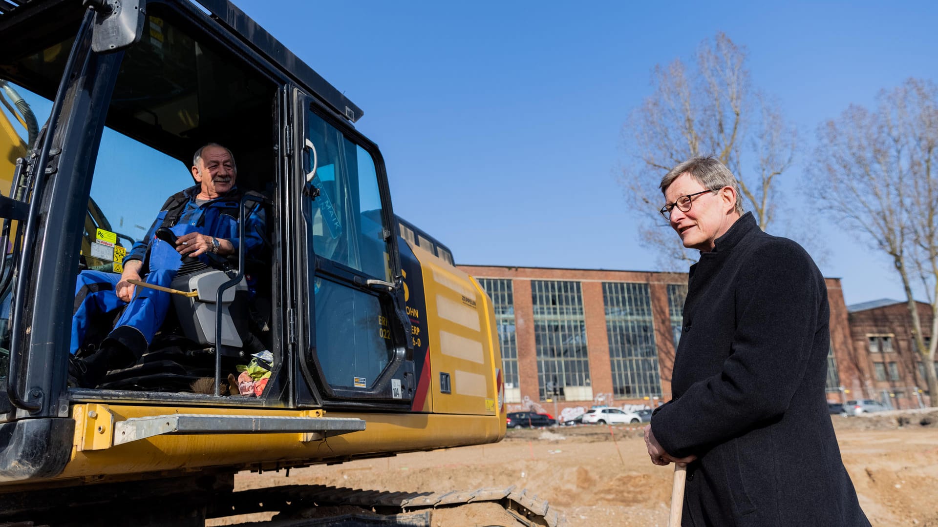 Der Kardinal will Volksnähe zeigen: Er spricht auf der Baustelle des Erzbischöflichen Bildungscampus beim Spatenstich mit Baggerfahrer Mike.