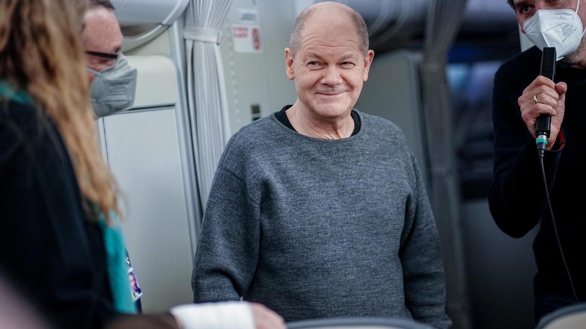 Olaf Scholz im Flieger nach Washington – inklusive des nun berühmten Pullovers.