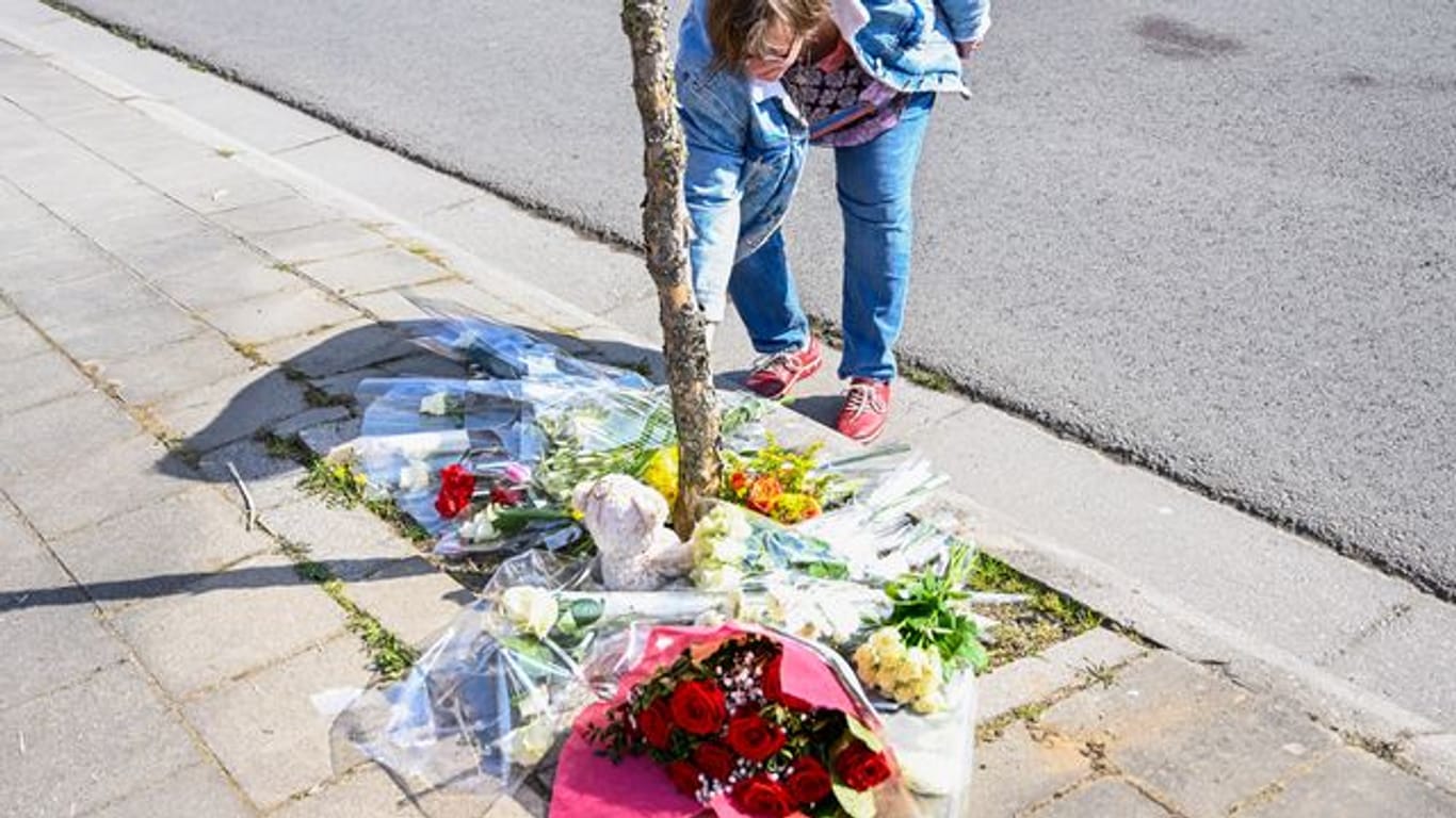 Eine Frau legt Blumen an der Unfallstelle nieder.