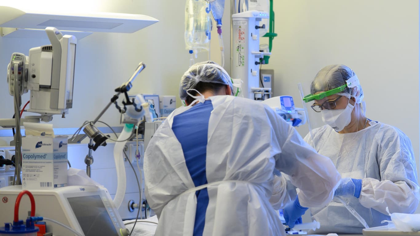 Pflegerinnen an einem Krankenhausbett: Die Zahl der Corona-Ansteckungen in Deutschland liegt weiterhin auf hohem Niveau.