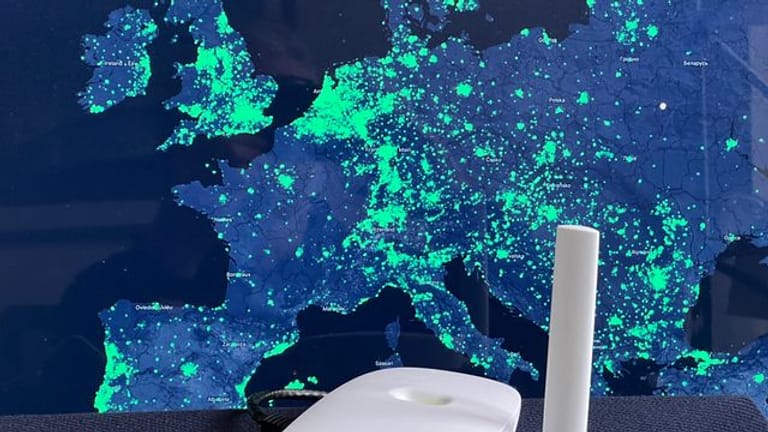 Ein Funk-Hotspot des Helium-Netzwerks vor einer Karte der Netzabdeckung in Europa.