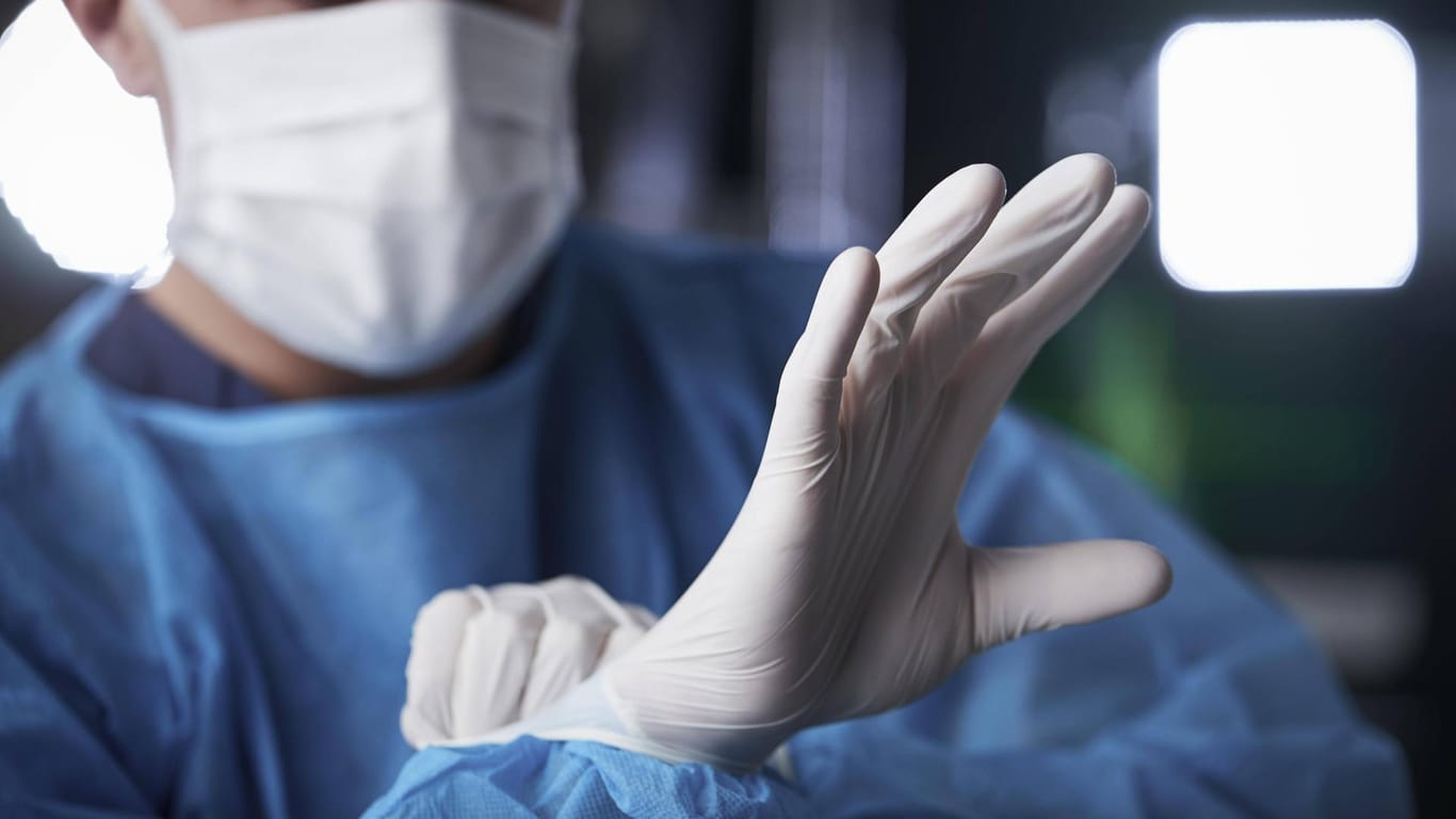 Mann zieht sich medizinische Handschuhe an (Symbolbild): Der Chirurg erhielt von der Ärztekammer ein vorläufiges Berufsverbot.