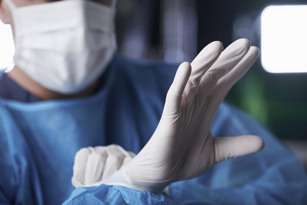 Mann zieht sich medizinische Handschuhe an (Symbolbild): Der Chirurg erhielt von der Ärztekammer ein vorläufiges Berufsverbot.