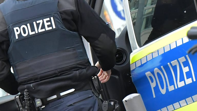 Polizist steigt in einen Streifenwagen (Symbolbild): In Bonn wird das Verhalten eines Polizeibeamten derzeit geprüft.