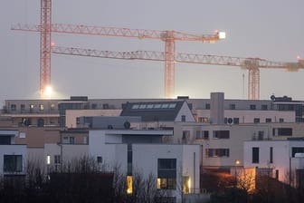 Kräne auf einer Baustelle für Wohnungen stehen hinter Mehrfamilienhäusern des relativ neuen Stadtteils Kalbach-Riedberg in Frankfurt.
