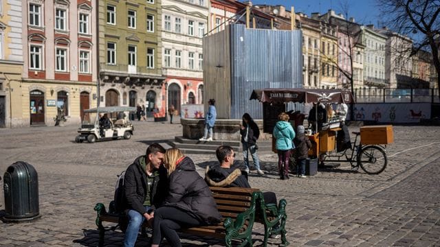 Ein küssendes Paar sitzt in der Innenstadt von Lwiw auf einer Bank.