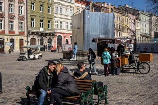 Ein küssendes Paar sitzt in der Innenstadt von Lwiw auf einer Bank.