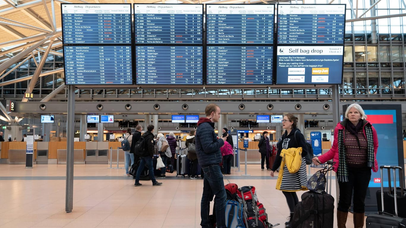 Menschen stehen vor Anzeigetafeln im Flughafen (Symbolbild): In Hamburg könnte es zu einem Streik des Bodenpersonals kommen.