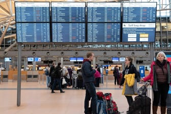 Menschen stehen vor Anzeigetafeln im Flughafen (Symbolbild): In Hamburg könnte es zu einem Streik des Bodenpersonals kommen.