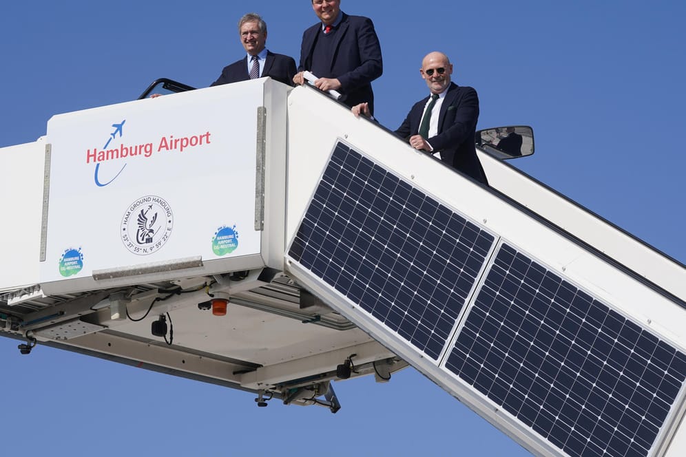 Michael Eggenschwiler (l-r), Vorsitzender der Geschäftsführung am Hamburg Airport, Andreas Dressel, und Michael Westhagemann stehen auf einer Passagiertreppe, an der Solarpanel angebracht sind: Der Hamburger Flughafen hat sich als erster deutscher Airport für CO2-neutral erklärt.