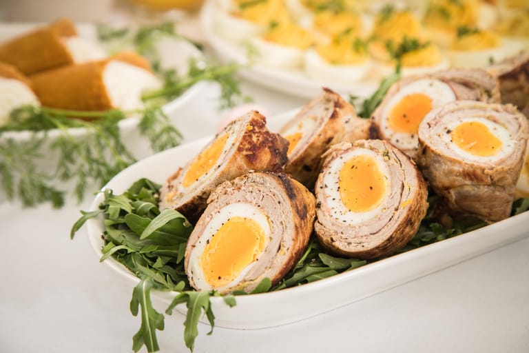 Für die Schwalbennester wird ein Schweineschnitzel plattiert und mit Senf bestrichen. Dann werden geräucherter Schinken und gekochte Eier auf dem Fleisch verteilt und eingerollt. Das Ganze kommt als Braten in den Ofen.
