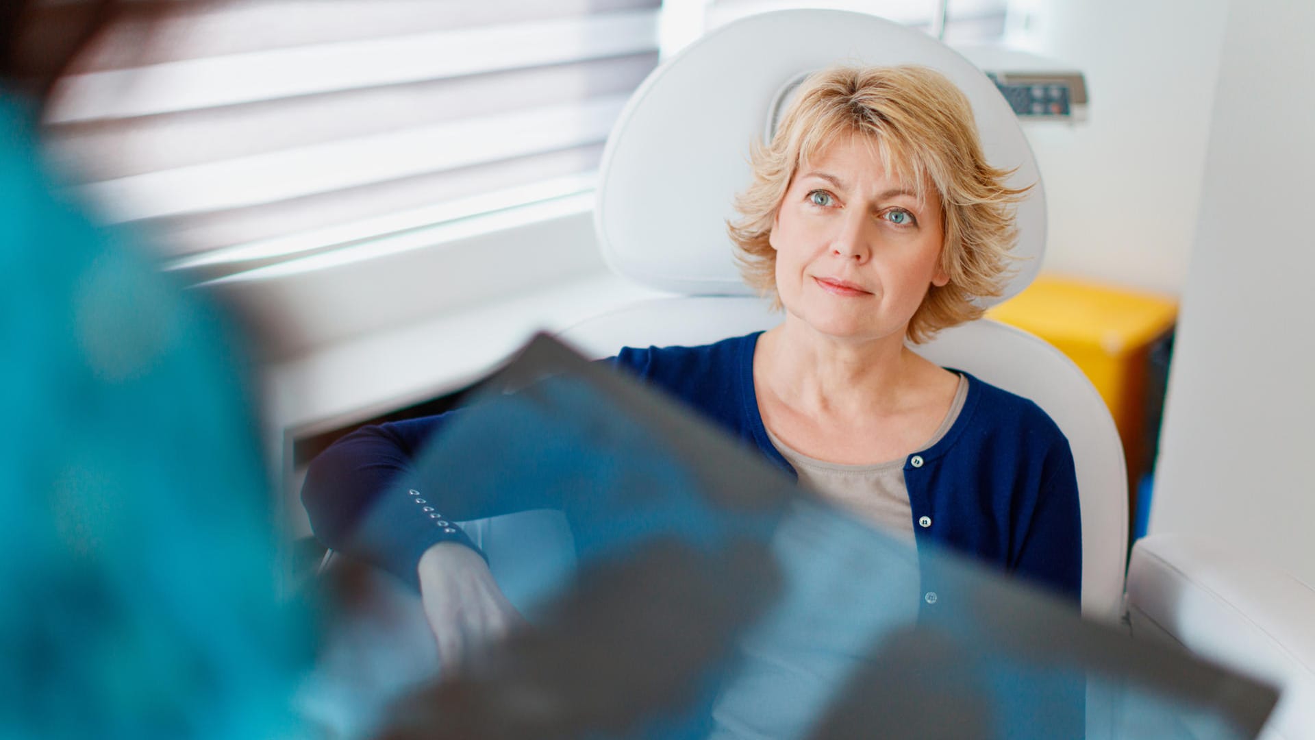 Patientin wartet auf Ergebnis vom Arzt, der ein Röntgenbild in der Hand hält