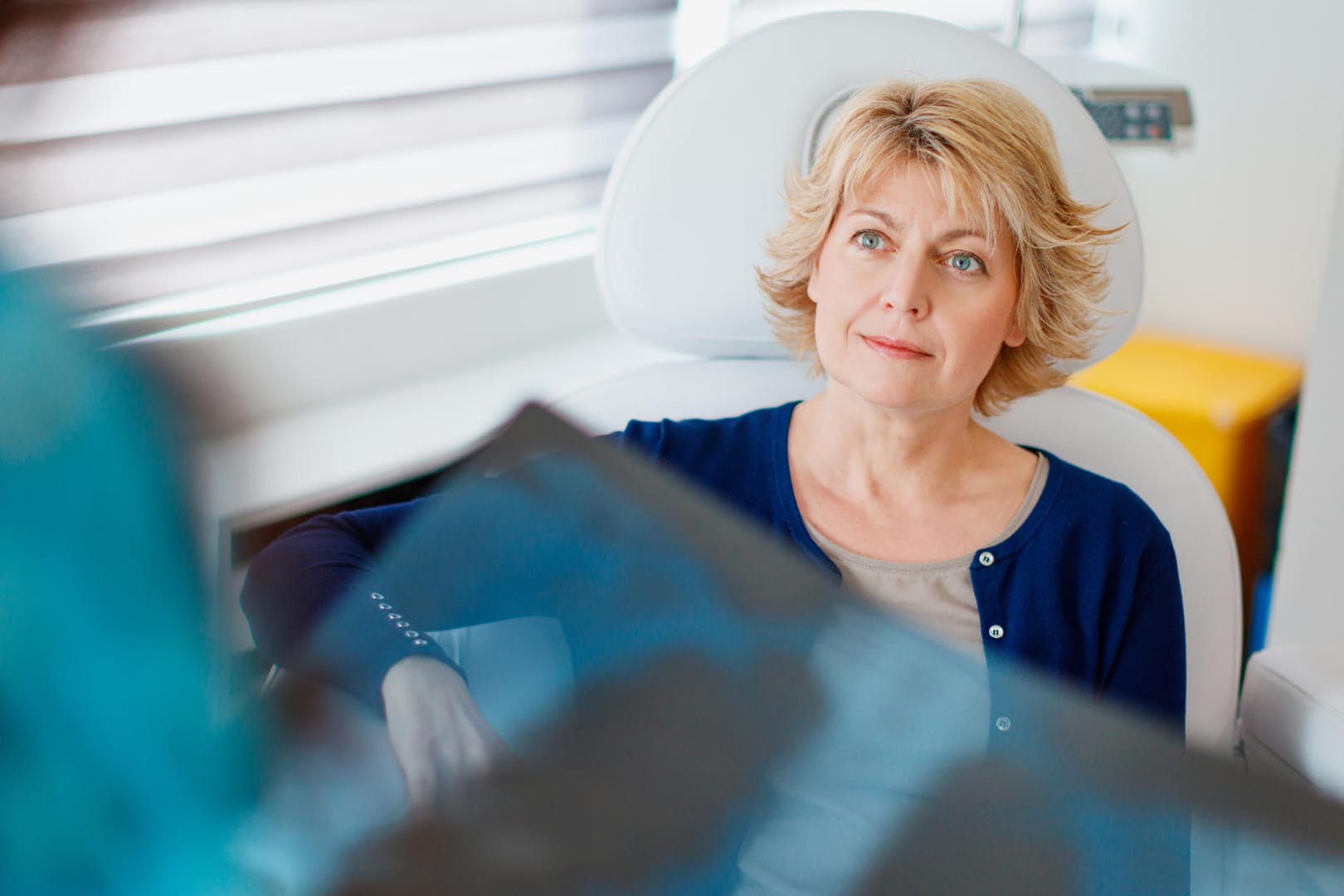 Patientin wartet auf Ergebnis vom Arzt, der ein Röntgenbild in der Hand hält