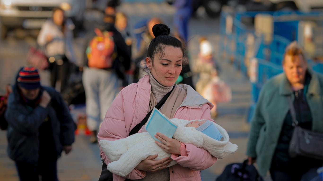 Eine Frau trägt ihr Kind über die ukrainisch-rumänsiche Grenze.
