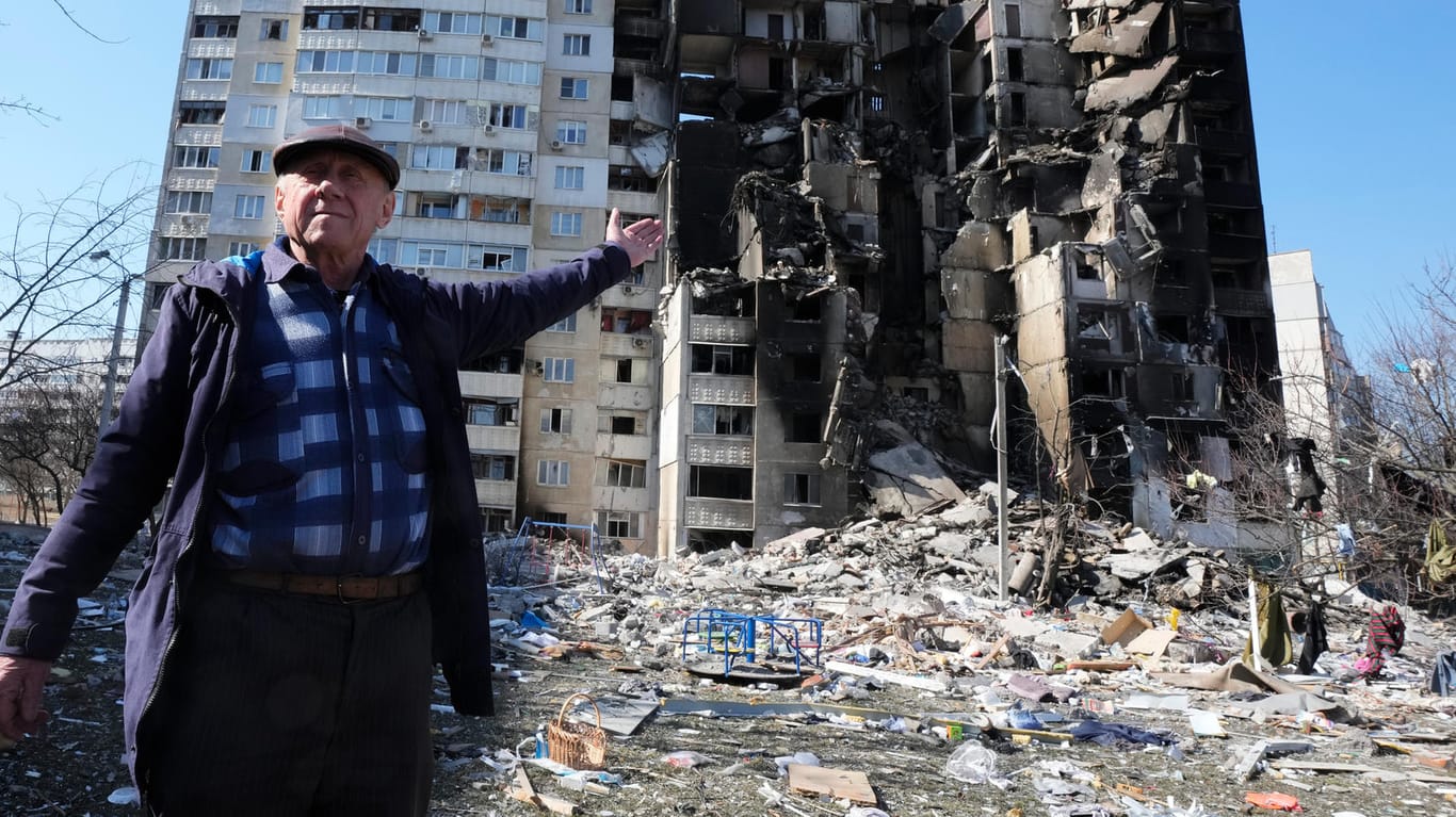 Ein Mann zeigt auf sein zerstörtes Wohngebäude nach einem russischen Bombenangriff in Charkiw.