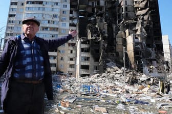 Ein Mann zeigt auf sein zerstörtes Wohngebäude nach einem russischen Bombenangriff in Charkiw.