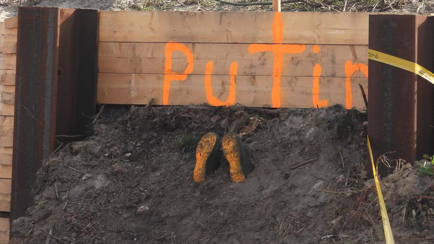 Unter einem Brett, auf dem Putin steht, stecken zwei Schuhe in der Erde. Bisher ist nicht klar, wer für die Aktion verantwortlich ist. Unter einem Brett, auf dem Putin steht, stecken zwei Schuhe in der Erde. Bisher ist nicht klar, wer für die Aktion verantwortlich ist.