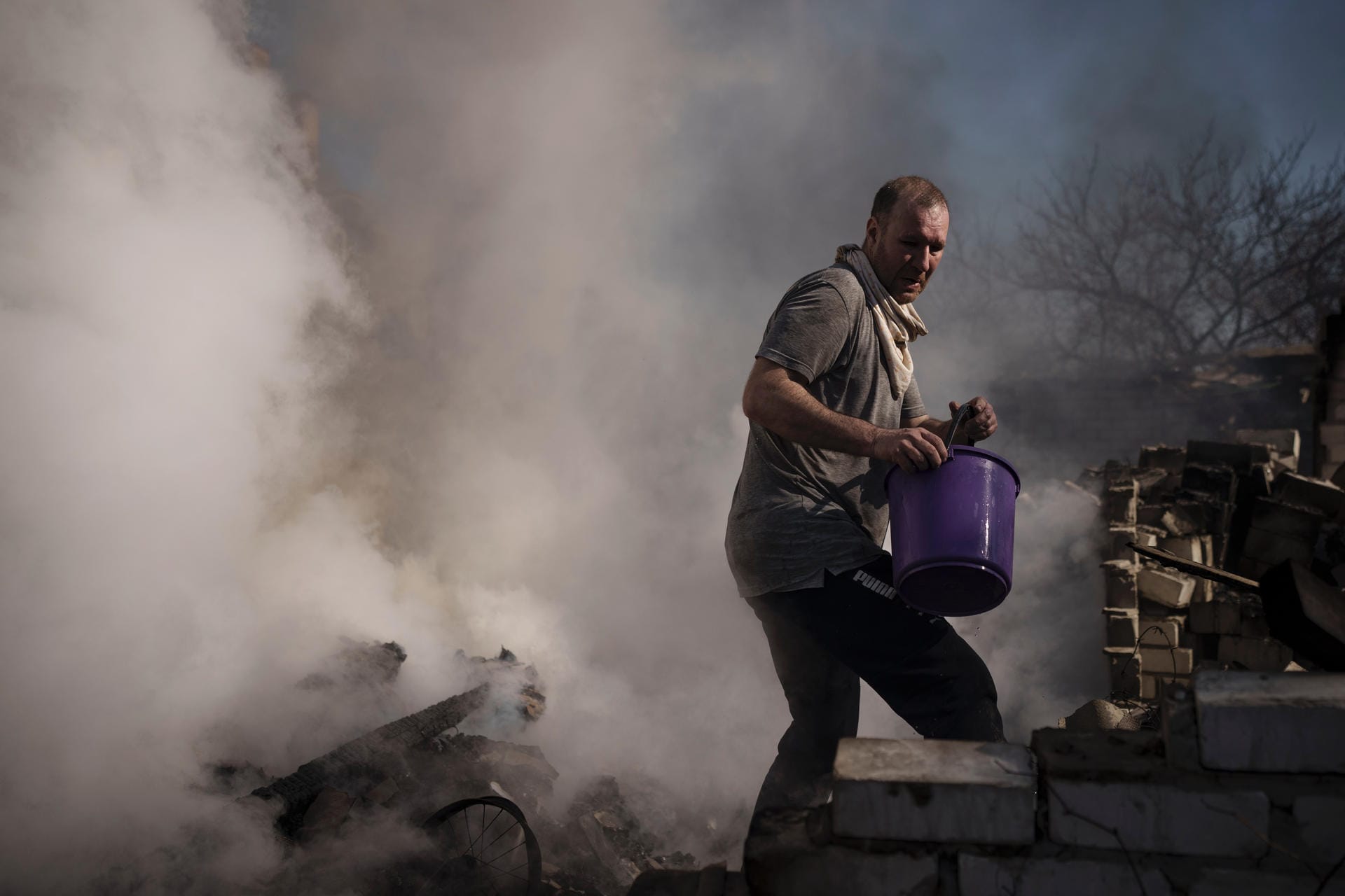 Charkiw im Osten der Ukraine: Ein Mann versucht das Feuer im Haus seiner Nachbarn zu löschen, das bei einem russischen Angriff zerstört wurde. Die Stadt steht seit Wochen unter Beschuss.