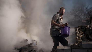 Charkiw im Osten der Ukraine: Ein Mann versucht das Feuer im Haus seiner Nachbarn zu löschen, das bei einem russischen Angriff zerstört wurde. Die Stadt steht seit Wochen unter Beschuss.