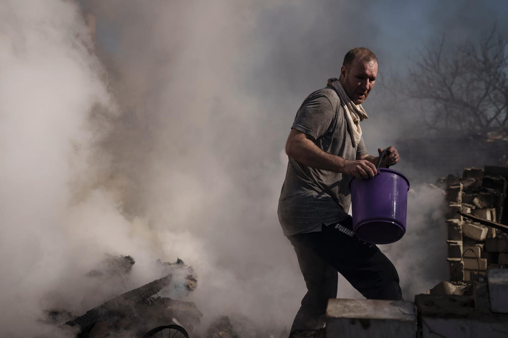 Charkiw im Osten der Ukraine: Ein Mann versucht das Feuer im Haus seiner Nachbarn zu löschen, das bei einem russischen Angriff zerstört wurde. Die Stadt steht seit Wochen unter Beschuss.