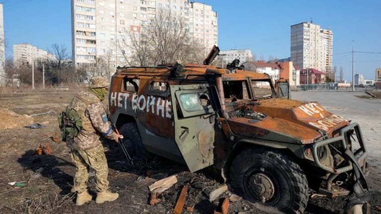 Ein ukrainischer Soldat inspiziert einen zerstörten russischen Schützenpanzer in Charkiw.