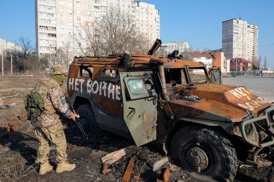 Ein ukrainischer Soldat inspiziert einen zerstörten russischen Schützenpanzer in Charkiw.