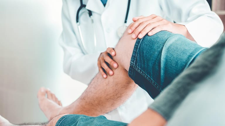 Ärztin begutachtet das Bein eines Patienten.