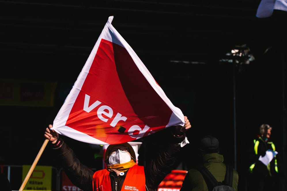 Eine streikende Arbeitnehmerin mit Verdi-Fahne (Symbolbild): In mehreren Städten sind Warnstreiks geplant.