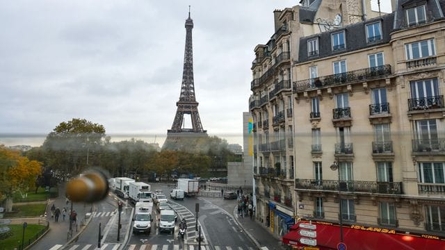 Aus dem Fenster der Pariser Metro ist hinter Wohnhäusern der Eiffelturm zu sehen - samt des üblichen Straßenrkehrs.