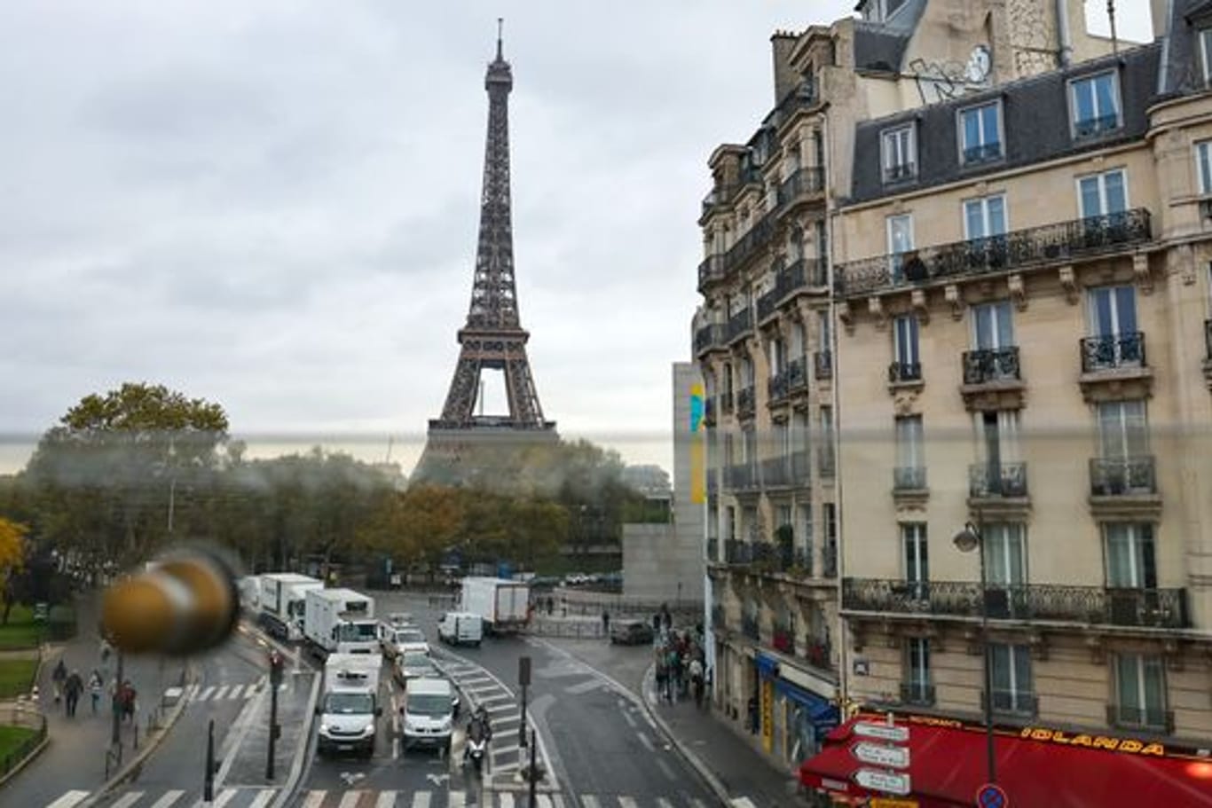 Aus dem Fenster der Pariser Metro ist hinter Wohnhäusern der Eiffelturm zu sehen - samt des üblichen Straßenrkehrs.