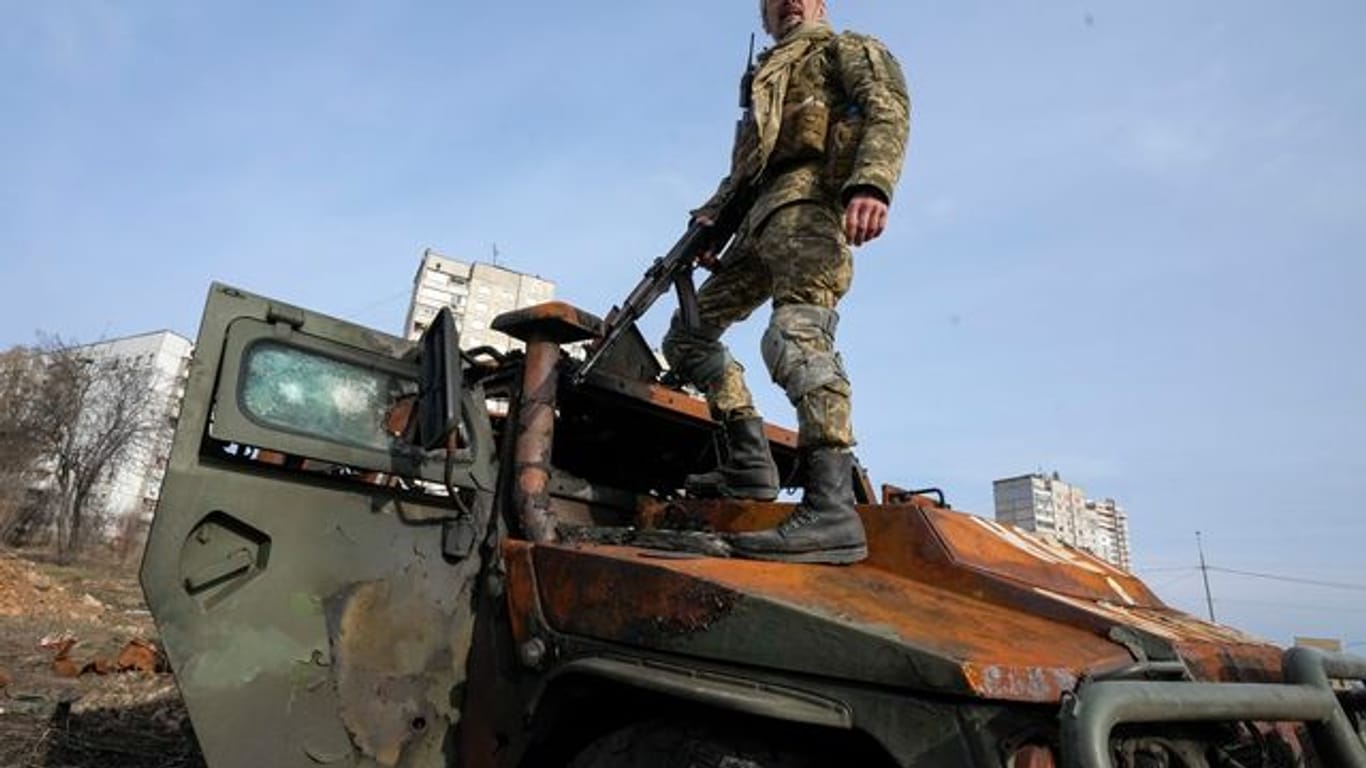 Ein ukrainischer Soldat steht nach einem Gefecht auf einem zerstörten russischen Schützenpanzer.