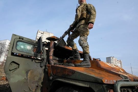 Ein ukrainischer Soldat steht nach einem Gefecht auf einem zerstörten russischen Schützenpanzer.