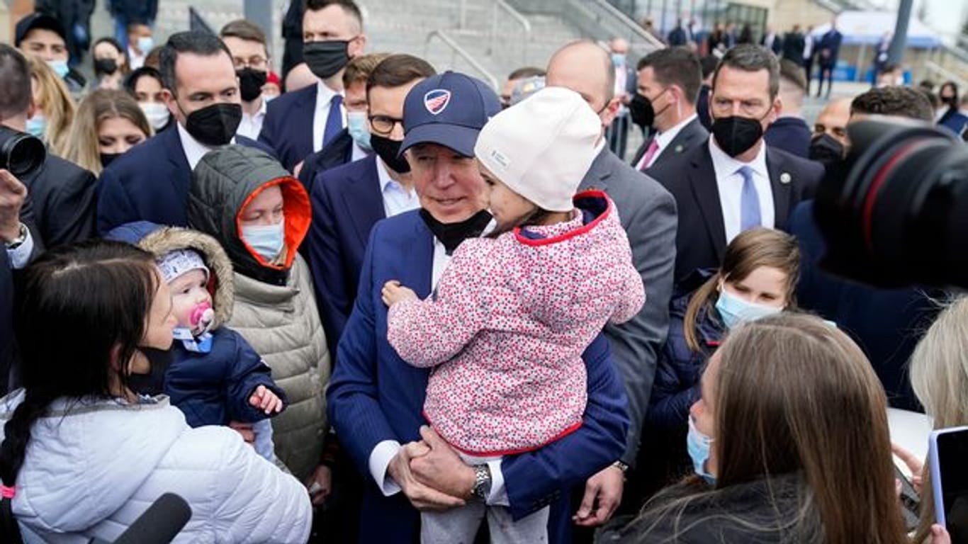 Joe Biden trägt bei seinem Besuch im PGE Narodowy-Stadion, in dem ukrainische Kriegsflüchtlinge untergebracht sind, ein Kind.