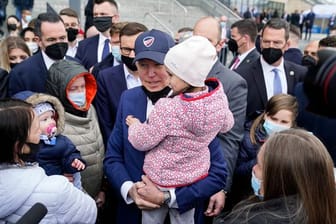 Joe Biden trägt bei seinem Besuch im PGE Narodowy-Stadion, in dem ukrainische Kriegsflüchtlinge untergebracht sind, ein Kind.