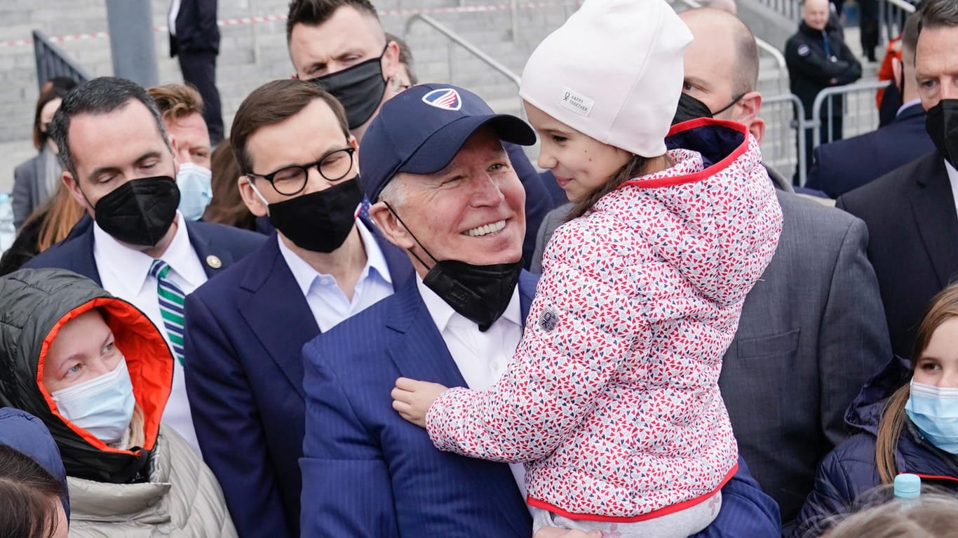 Joe Biden trägt ein ukrainisches Flüchtlingskind auf dem Arm.