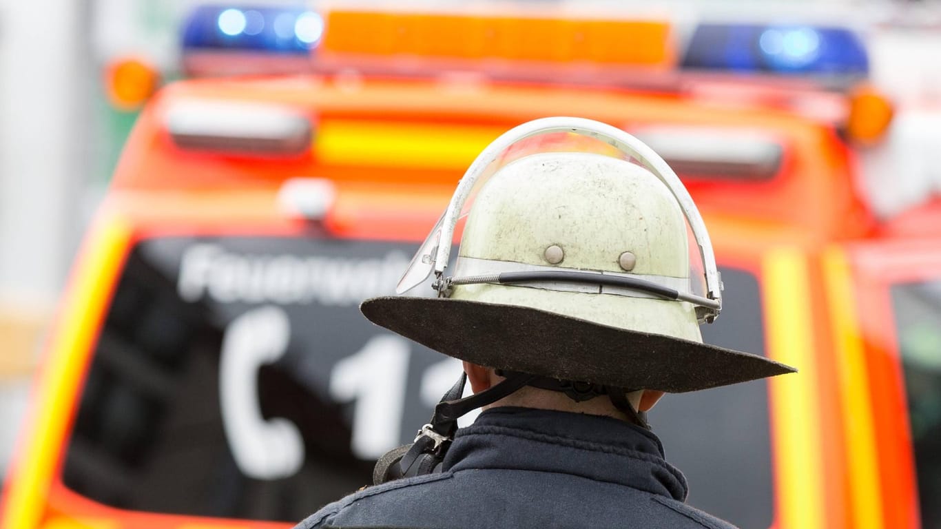 Ein Feuerwehrmann steht vor einem Einsatzfahrzeug (Symbolbild): In Bayern hatte eine Kettensäge einen Fahrzeugbrand verursacht.