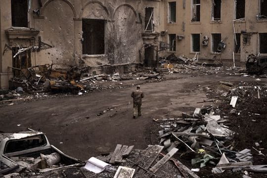 Ein ukrainischer Soldat geht an einem schwer beschädigten regionalen Verwaltungsgebäude in Charkiw vorbei.