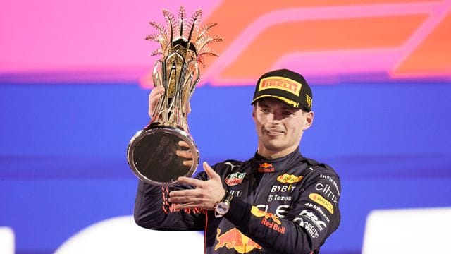 Rennfahrer Max Verstappen hält den Grand-Prix-Pokal in die Höhe.