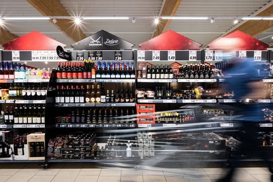 Ein Mann geht mit seinem Einkaufswagen in einem Discounter an Produkten vorbei.