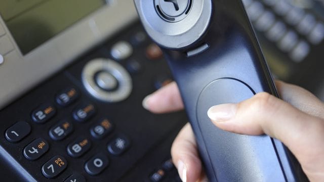 Eine Frau hält einen Telefonhörer in der Hand.