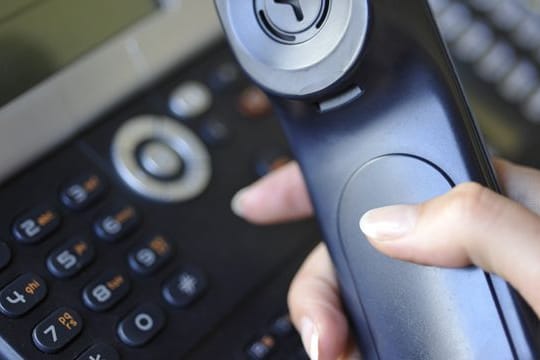 Eine Frau hält einen Telefonhörer in der Hand.