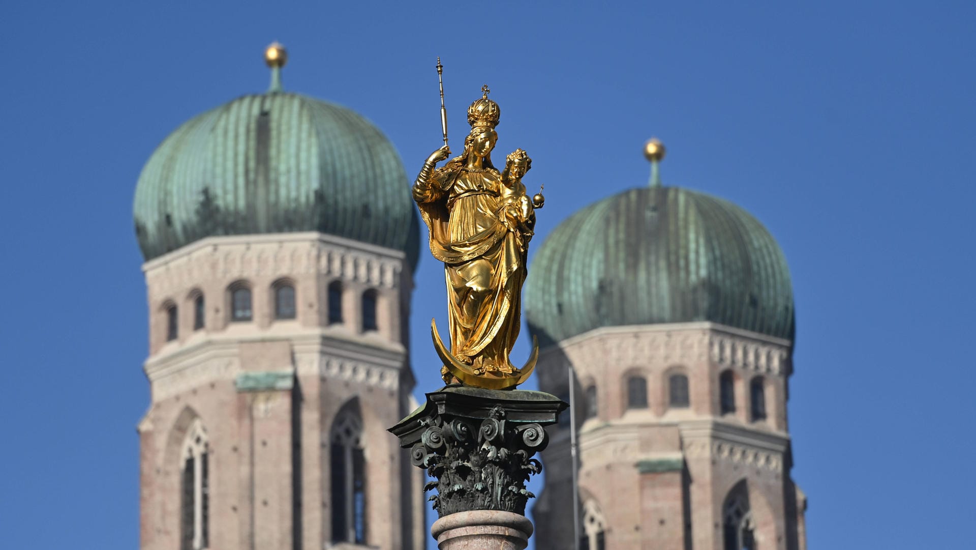 Goldene Madonna der Mariensäule auf dem Marienplatz in München. Im Hintergrund die Türme der Frauenkirche (Archivbild): Der Abgang von Kirchenrichter Wolf ist im Missbrauchsskandal nur ein Tropfen auf dem heißen Stein.