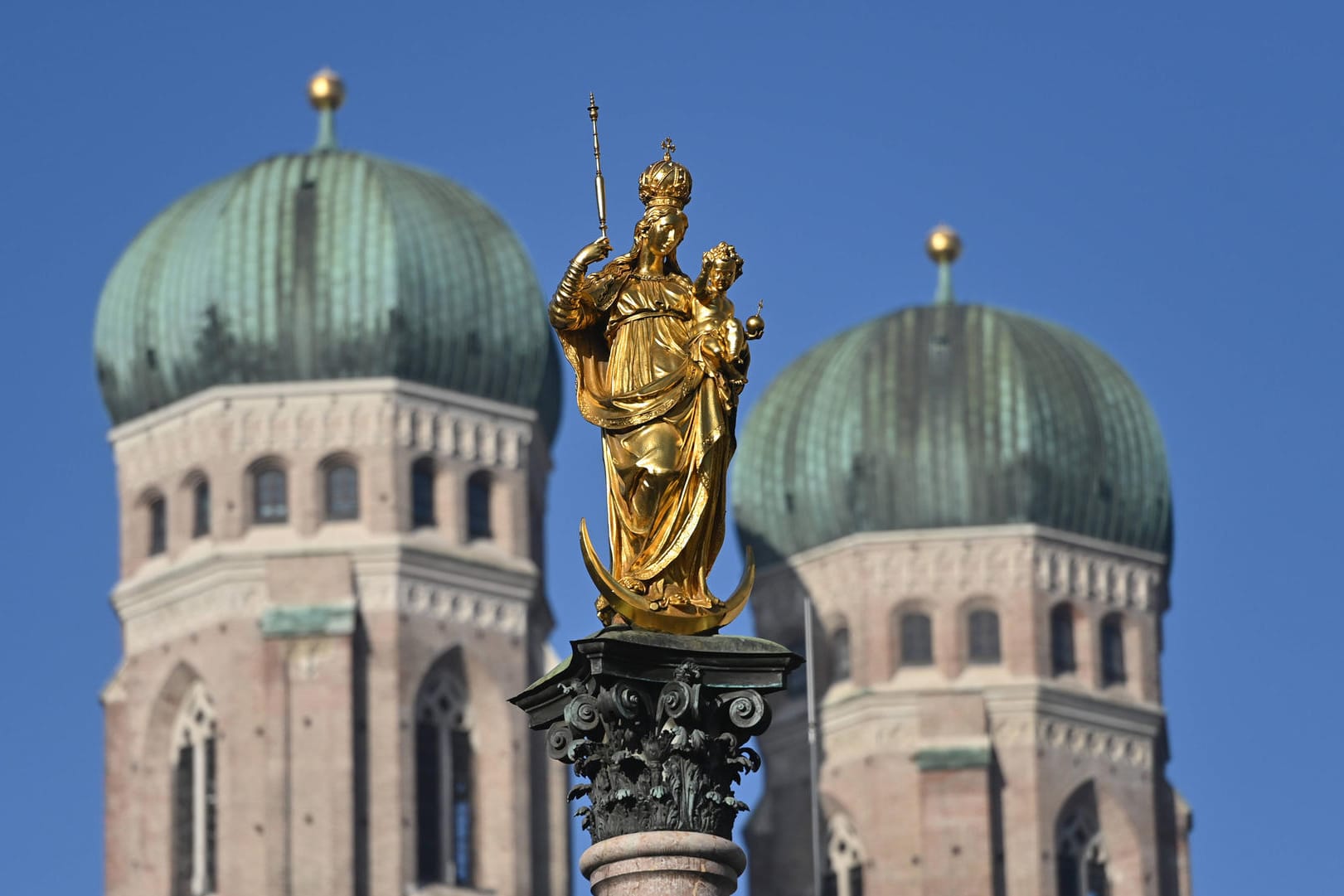 Goldene Madonna der Mariensäule auf dem Marienplatz in München. Im Hintergrund die Türme der Frauenkirche (Archivbild): Der Abgang von Kirchenrichter Wolf ist im Missbrauchsskandal nur ein Tropfen auf dem heißen Stein.