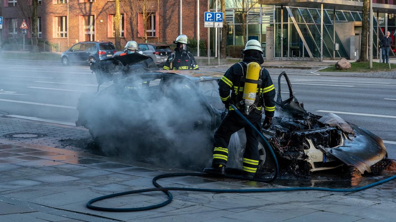 Ein Feuerwehrmann steht vor dem verbrannten Auto: Der Fahrer konnte das Taxi noch rechtzeitig abstellen und sich retten.