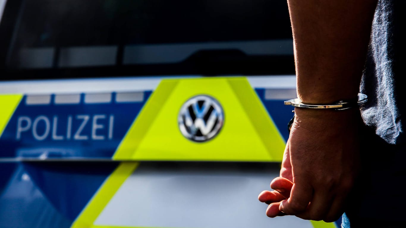Eine Person in Handschellen vor einem Einsatzfahrzeug der Polizei (Symbolbild): Am Hauptbahnhof Frankfurt am Main wurde ein Maskenverweigerer wegen Hitlergruß festgenommen.