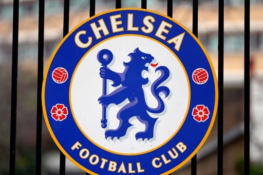 Das Logo des Fußballvereins Chelsea ist an einem Tor am Fußballstadion "Stamford Bridge" angebracht.